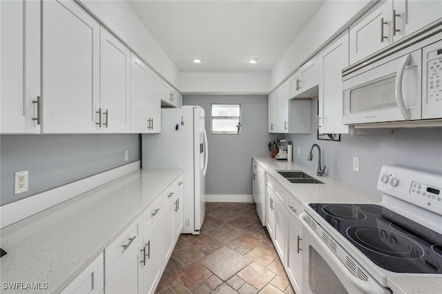 kitchen with light stone countertops, white cabinets, and white appliances