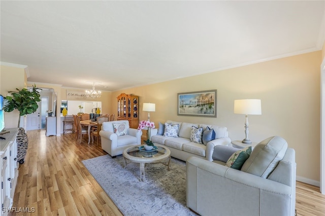 living room featuring ornamental molding, light hardwood / wood-style floors, and an inviting chandelier