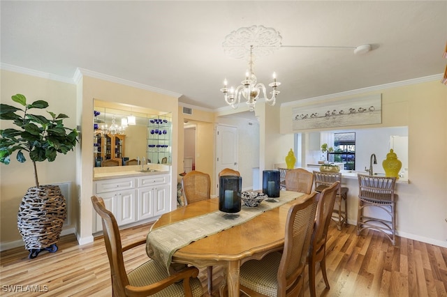 dining room with ornamental molding, a chandelier, and light hardwood / wood-style floors