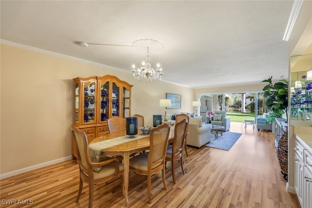 dining space with light hardwood / wood-style floors, crown molding, and a notable chandelier