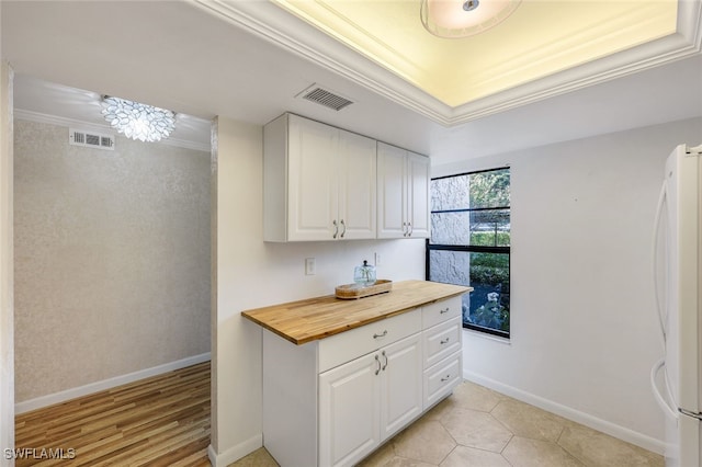 kitchen with wood counters, crown molding, white cabinets, and white refrigerator