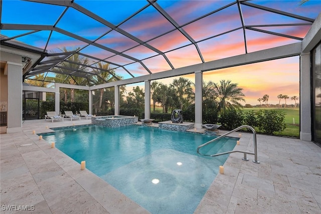 pool at dusk with glass enclosure, a patio area, and an in ground hot tub