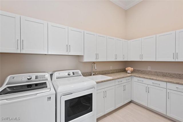 washroom featuring washer and clothes dryer, sink, cabinets, and light hardwood / wood-style flooring