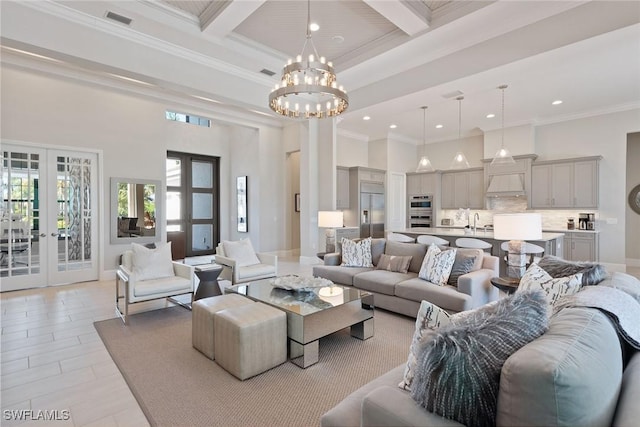 living room with beamed ceiling, a notable chandelier, ornamental molding, and french doors