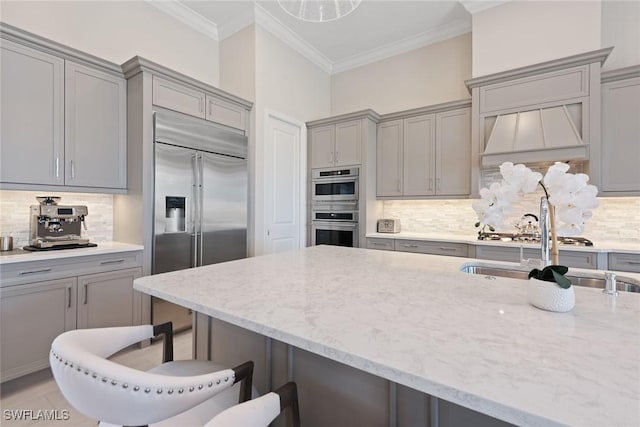 kitchen with a breakfast bar, backsplash, stainless steel appliances, and gray cabinets