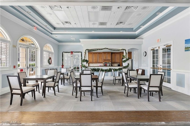 carpeted dining room with french doors, a towering ceiling, a tray ceiling, and crown molding