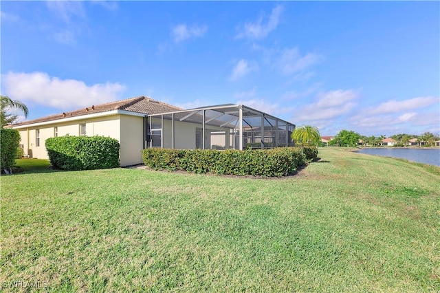 exterior space featuring a lawn, a lanai, and a water view