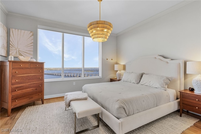 bedroom featuring a water view, light wood-type flooring, and crown molding