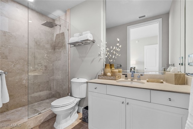 bathroom featuring tile patterned floors, vanity, toilet, and a tile shower