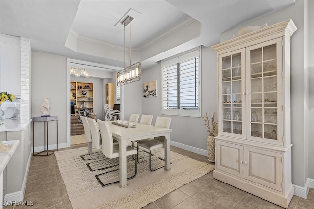 dining space featuring light tile patterned floors, a tray ceiling, and crown molding