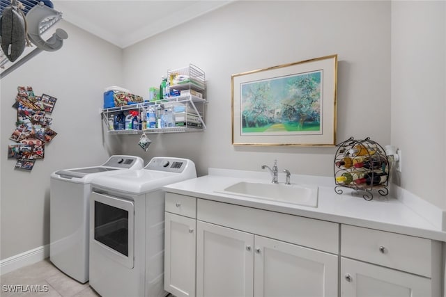 washroom with cabinet space, baseboards, washing machine and clothes dryer, a sink, and light tile patterned flooring