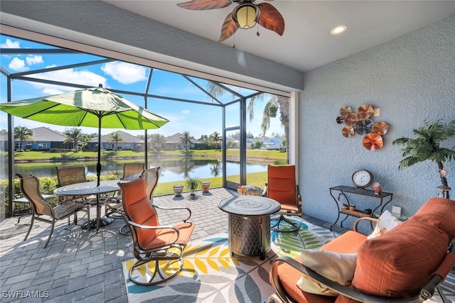 view of patio with a water view, ceiling fan, and a lanai