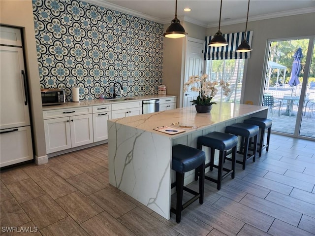 kitchen with decorative backsplash, light stone counters, hanging light fixtures, stainless steel appliances, and white cabinetry