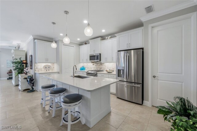 kitchen featuring decorative light fixtures, stainless steel appliances, light countertops, white cabinets, and a sink