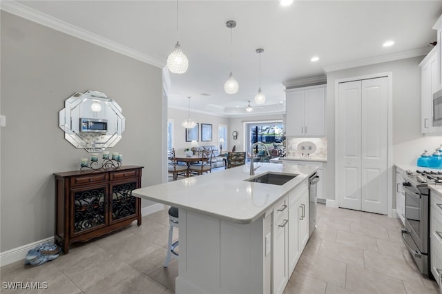 kitchen with white cabinets, a kitchen island with sink, stainless steel appliances, light countertops, and a sink