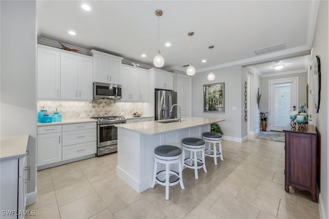 kitchen with stainless steel appliances, white cabinets, light countertops, an island with sink, and pendant lighting