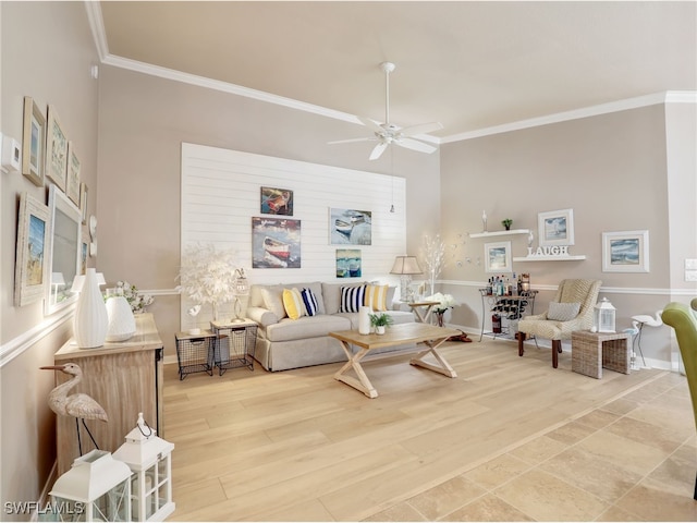 living room featuring ornamental molding, light wood-type flooring, a ceiling fan, and baseboards