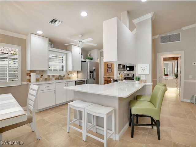 kitchen with stainless steel appliances, visible vents, a peninsula, and a breakfast bar area