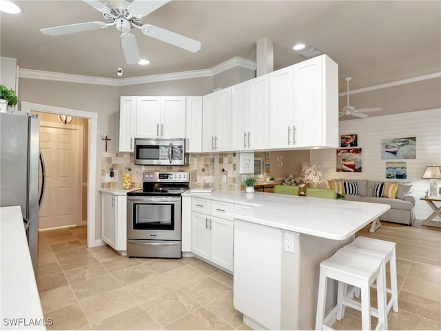 kitchen featuring a peninsula, open floor plan, appliances with stainless steel finishes, decorative backsplash, and crown molding