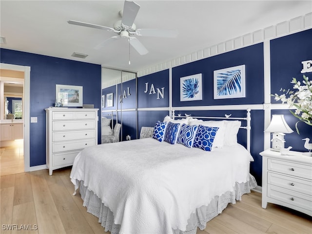 bedroom with a closet, light wood-type flooring, visible vents, and a ceiling fan