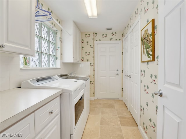 laundry area with visible vents, baseboards, independent washer and dryer, cabinet space, and wallpapered walls