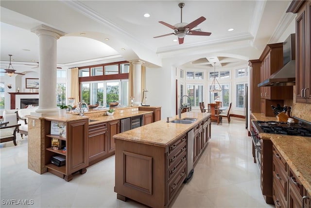 kitchen featuring sink, wall chimney exhaust hood, light stone counters, and a kitchen island with sink