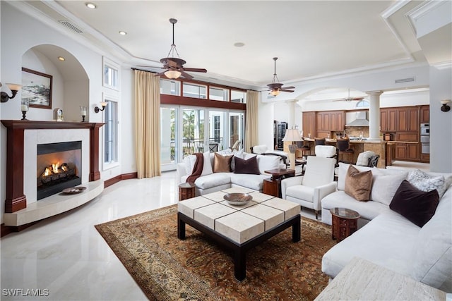 living room featuring ceiling fan, a tile fireplace, and ornamental molding