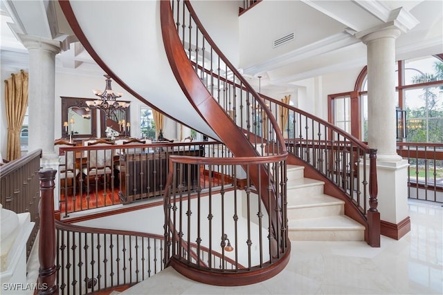 staircase featuring plenty of natural light, crown molding, a towering ceiling, and an inviting chandelier