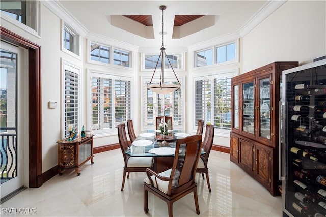 tiled dining room with a towering ceiling, crown molding, beverage cooler, and plenty of natural light