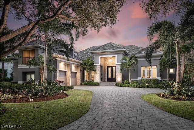 view of front of home featuring decorative driveway, a garage, french doors, and stucco siding