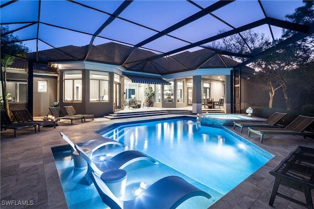 view of swimming pool with glass enclosure, a patio, and a pool with connected hot tub