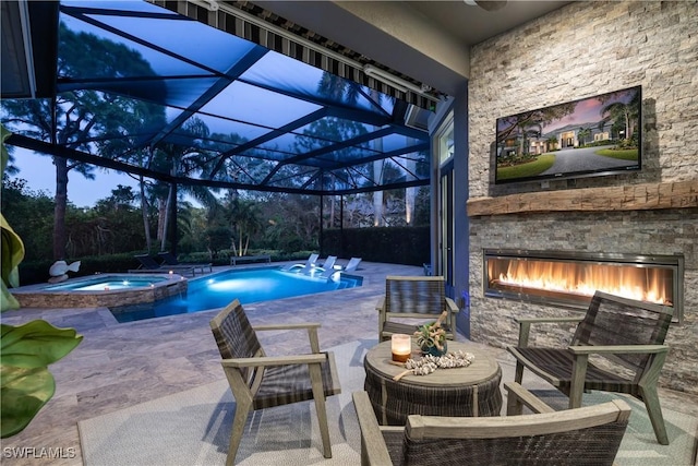 view of swimming pool with a lanai, a pool with connected hot tub, an outdoor stone fireplace, and a patio