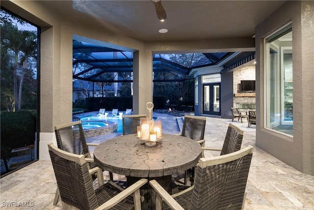 view of patio / terrace with a pool with connected hot tub, a lanai, french doors, outdoor dining area, and a ceiling fan