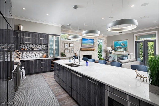 kitchen with a sink, open floor plan, modern cabinets, and ornamental molding