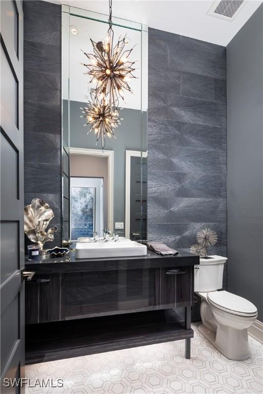 half bathroom featuring vanity, an inviting chandelier, toilet, and visible vents