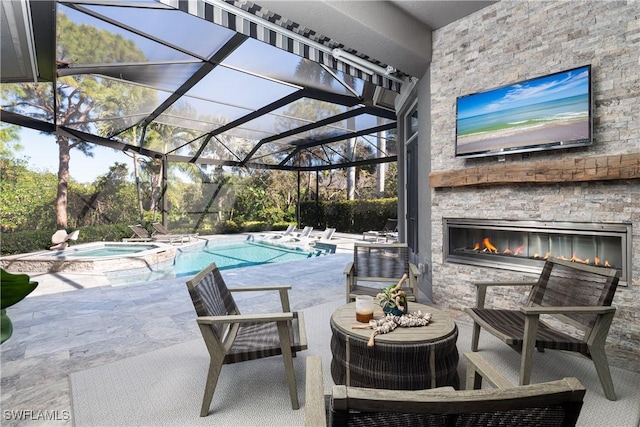 view of swimming pool with glass enclosure, a pool with connected hot tub, an outdoor stone fireplace, and a patio area