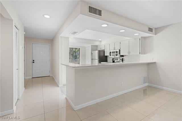 kitchen featuring white cabinets, light tile patterned flooring, kitchen peninsula, and appliances with stainless steel finishes