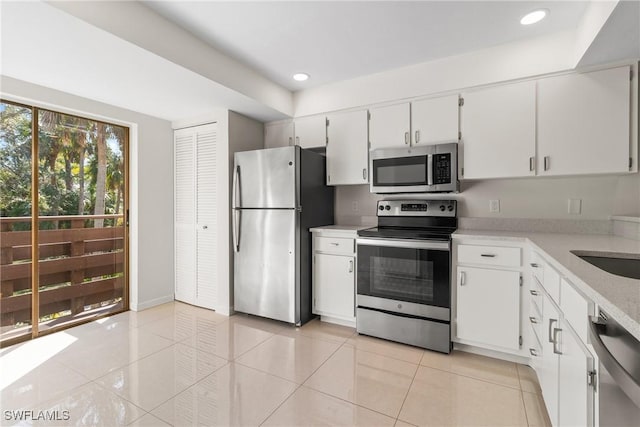 kitchen with light tile patterned floors, white cabinetry, and appliances with stainless steel finishes