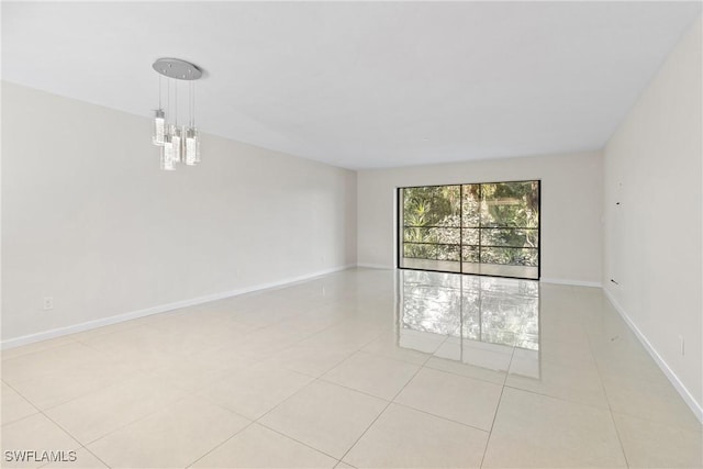 spare room featuring a notable chandelier and light tile patterned flooring