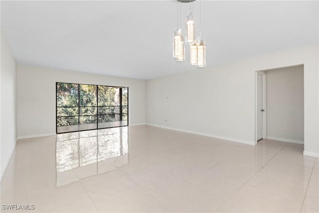 tiled spare room with a notable chandelier