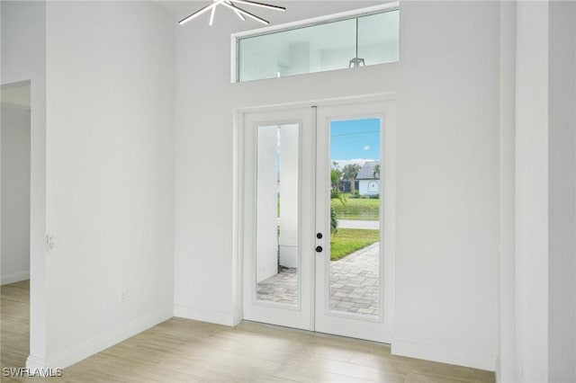 doorway to outside with french doors, light hardwood / wood-style flooring, and an inviting chandelier