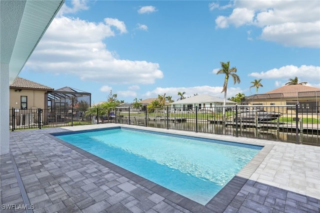 view of swimming pool featuring glass enclosure, a water view, and a patio