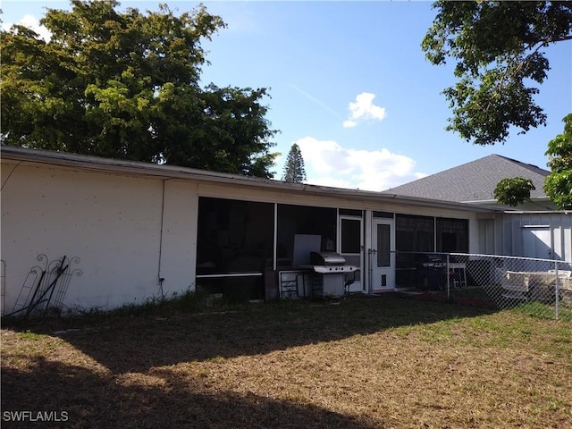 rear view of property with a yard and a sunroom