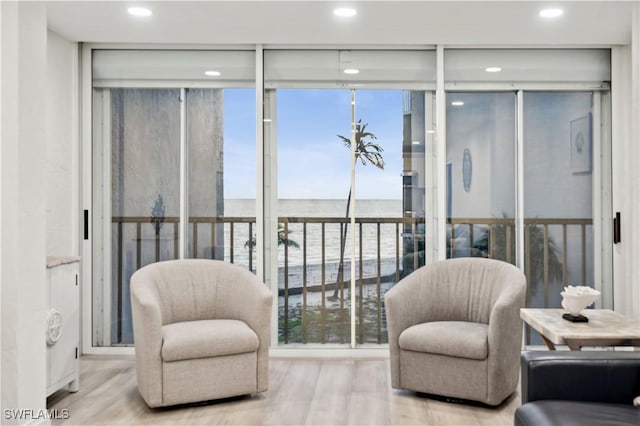 living area with a water view, expansive windows, and light hardwood / wood-style floors