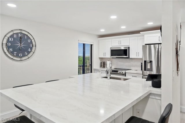 kitchen featuring white cabinetry, sink, a kitchen breakfast bar, kitchen peninsula, and appliances with stainless steel finishes