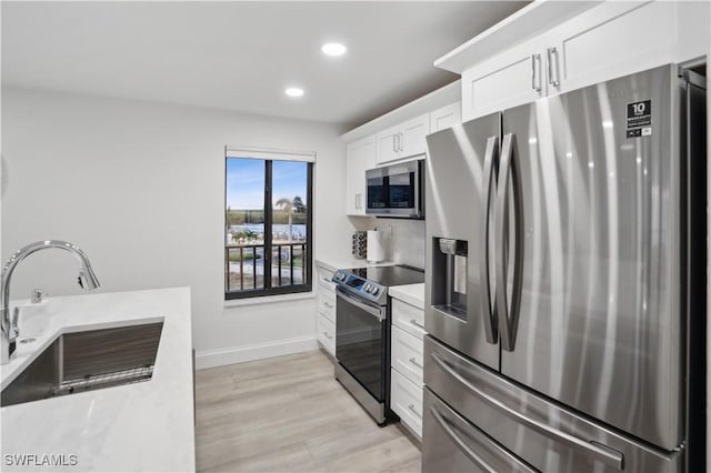 kitchen featuring sink, white cabinets, light wood-type flooring, and appliances with stainless steel finishes