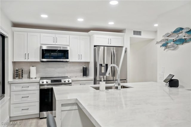 kitchen featuring light stone counters, white cabinets, and appliances with stainless steel finishes