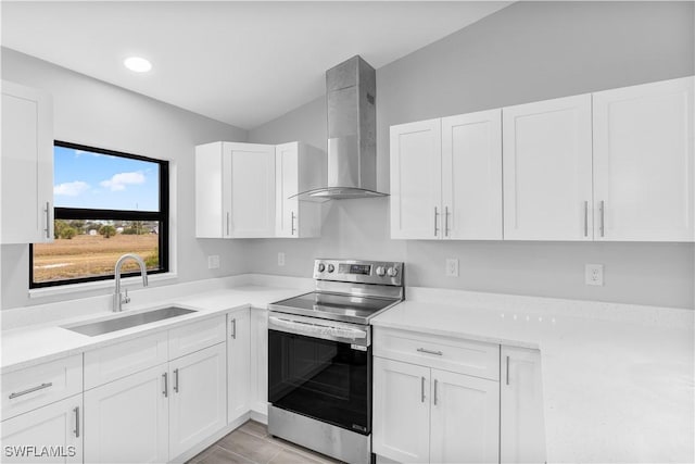 kitchen with sink, wall chimney range hood, light tile patterned flooring, stainless steel range with electric cooktop, and white cabinets