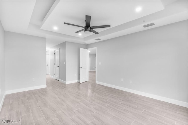 unfurnished room featuring ceiling fan and a raised ceiling