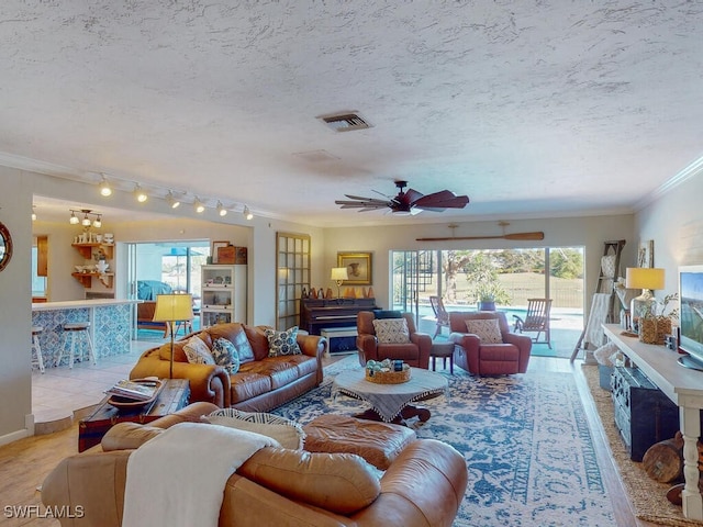 living room featuring ceiling fan, ornamental molding, and a textured ceiling